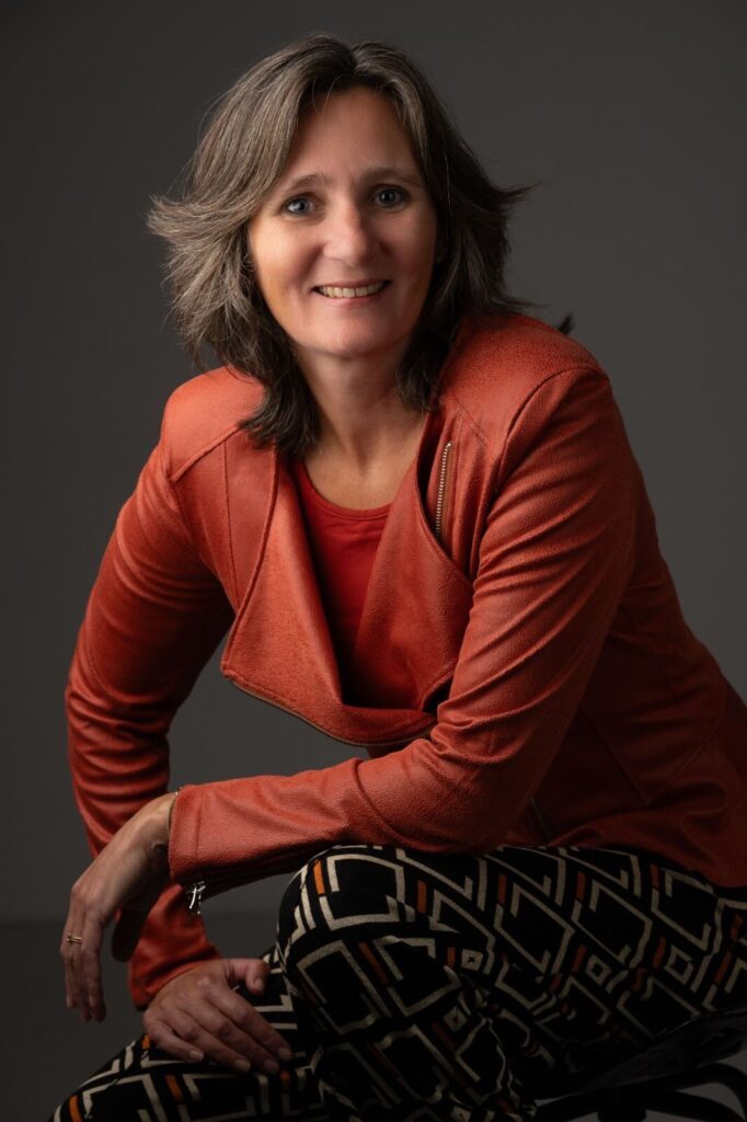 Portret van Karleen Wijsman, de warme en energieke masseuse , die met haar massages en meditaties mensen helpt ontdekken wat echt bij hen past. Ze draagt een rood jasje.