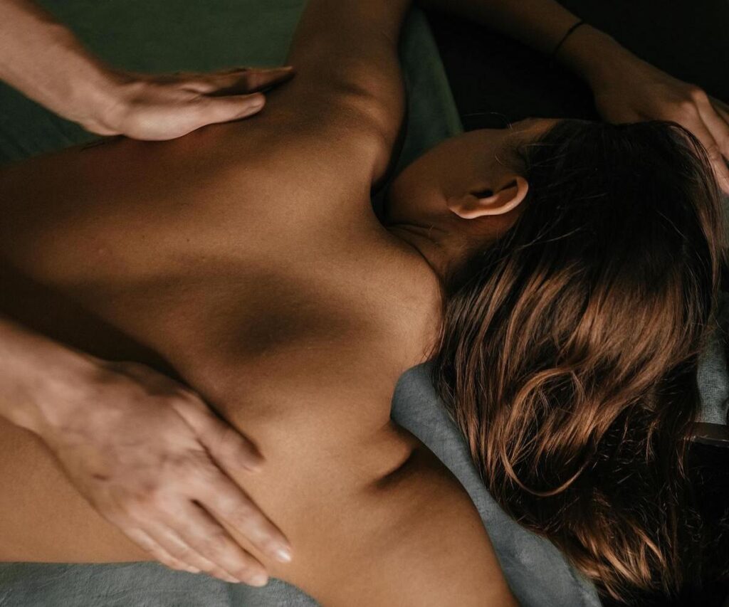 Vrouw ondergaat een ontspannende massage: de afbeelding toont de rug van de vrouw en de handen van de masseur tijdens de behandeling.
